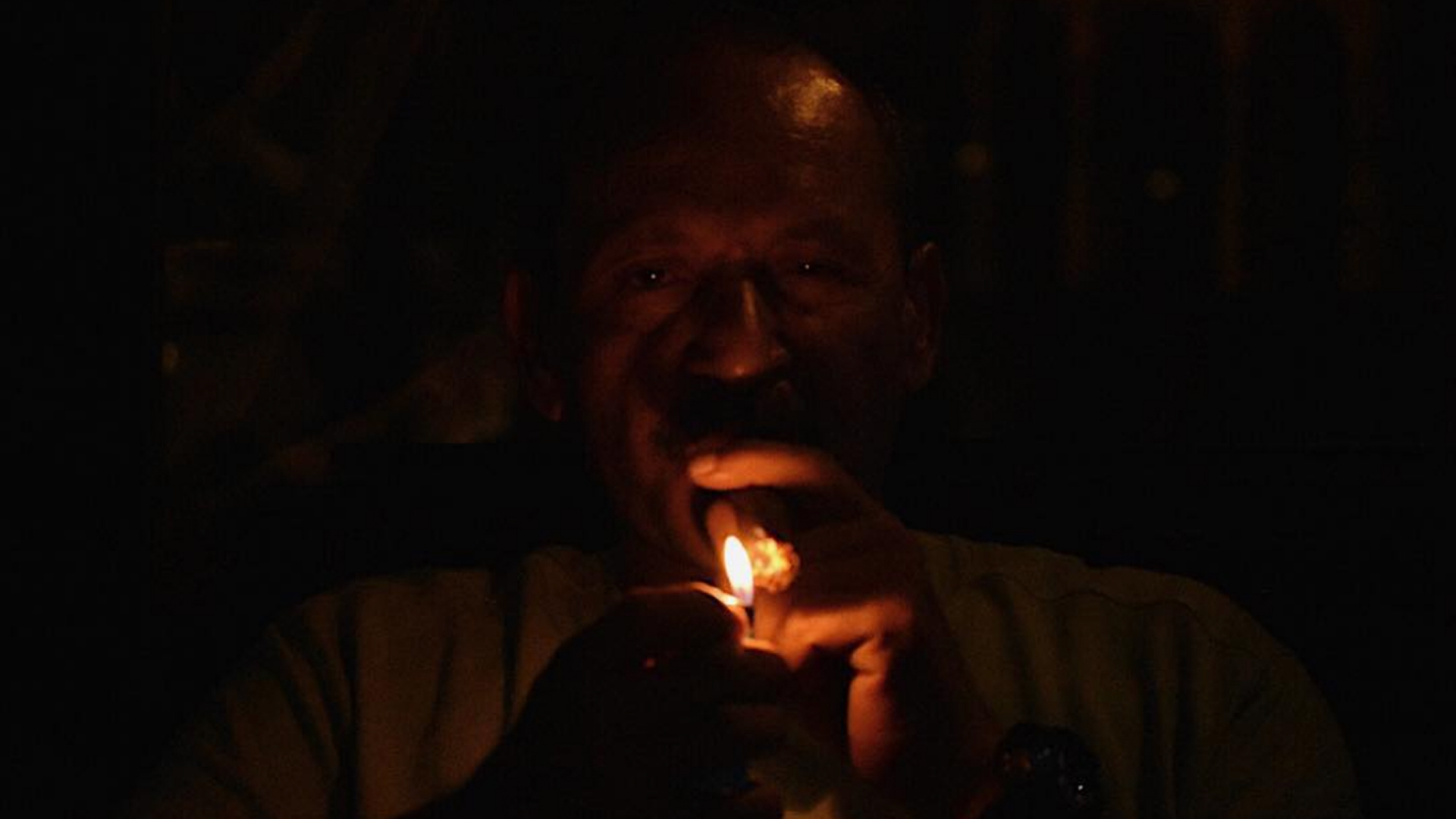 My father lighting up a cuban cigar in darkness